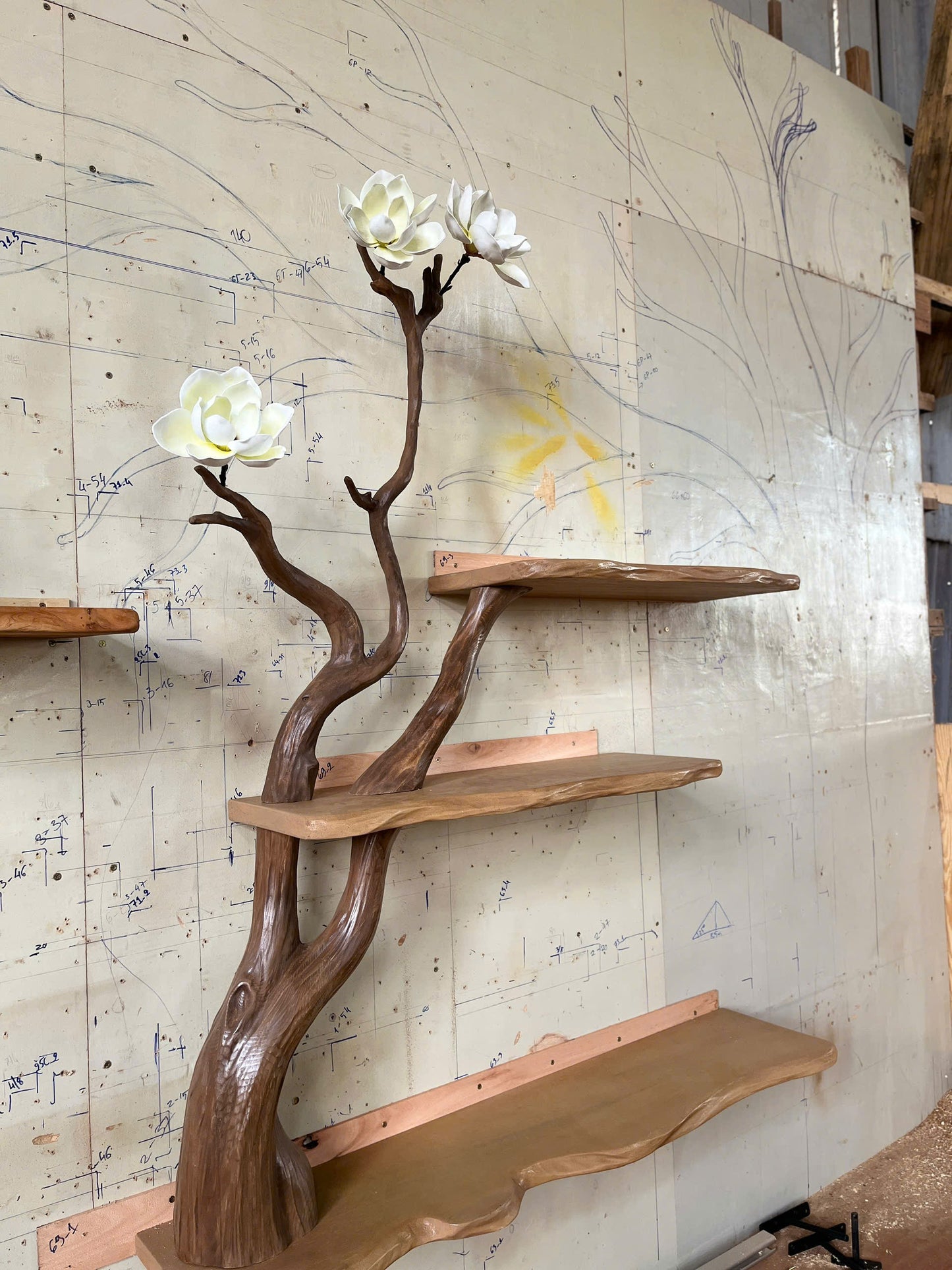 Wooden shelf with natural branch design against a wall with drawings