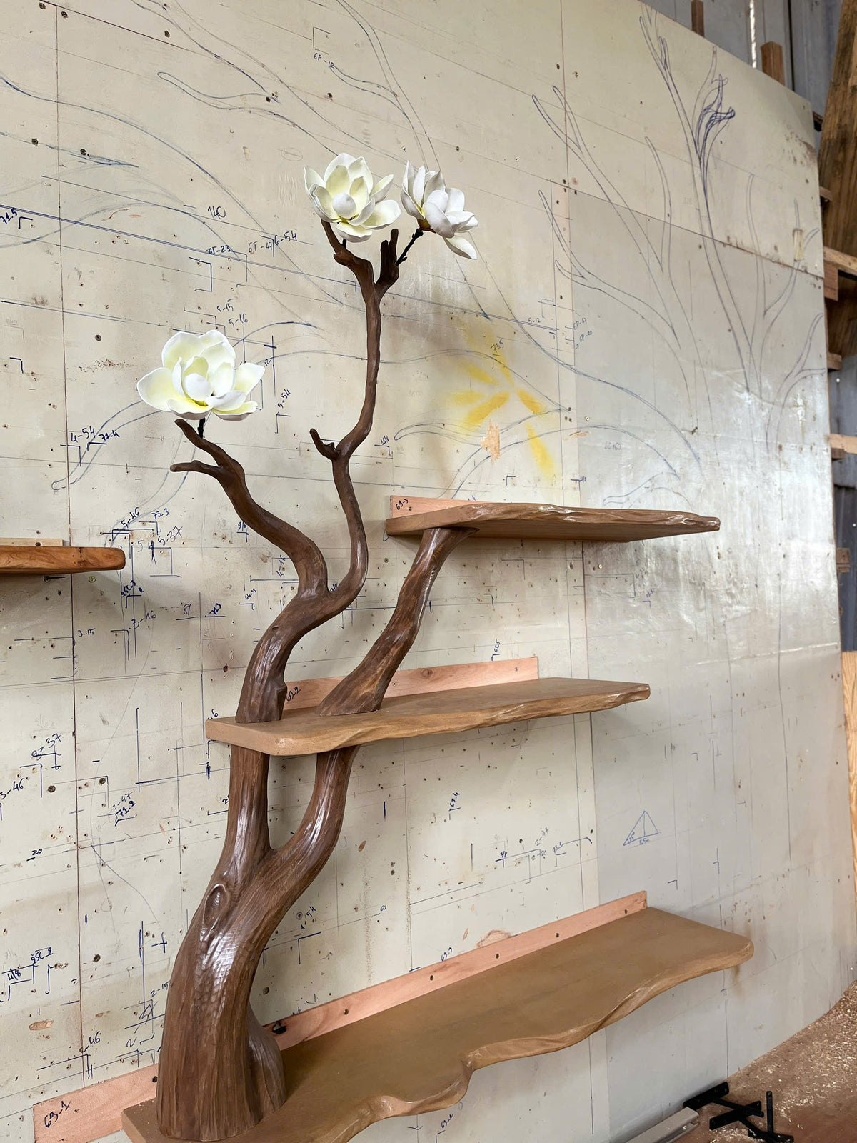 Wooden shelf with natural branch design against a wall with drawings